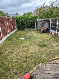 a backyard with a yard with a fence and grass at 3 bedroom mid terraced house (2 double & 1 single) in Grays Thurrock