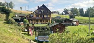 ein Haus auf einem Hügel mit Spielplatz in der Unterkunft Penzion Iva in Tanvald