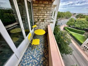 une table et des chaises jaunes sur le balcon d'une maison dans l'établissement Centre ville Dijon Wilson *Chez Charles* 2Ch, à Dijon