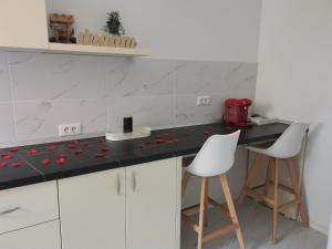 a kitchen with a black counter and two white chairs at Iași Jacuzzi Apartment F in Iaşi