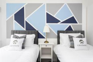 - 2 lits dans une chambre aux murs bleus et blancs dans l'établissement 30 Percent Off Monthly Stays - Free Parking - Sky & Netflix, à Borehamwood