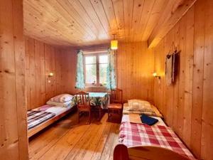 a room with two beds in a wooden cabin at Folwark Toporzysko in Jordanów