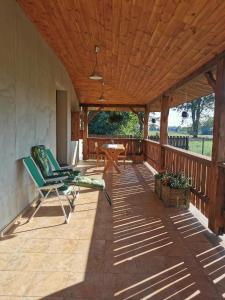 a wooden porch with chairs and a table on it at Siedlisko pod Orzechem in Przyłęk
