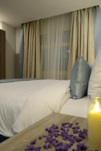 a bed with a candle and purple petals on it at Glamour Inn AL Nuzha -جلامور ان النزهة in Jeddah