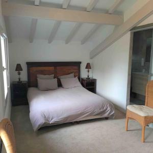 a bedroom with a white bed with two tables and a chair at Anglet Chiberta, les plages et le golf à pied. in Anglet