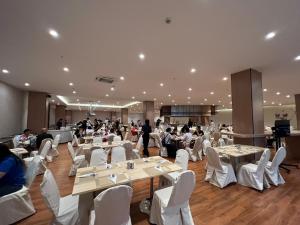 un salón de banquetes con mesas blancas y sillas blancas en The Srivaree Airport Hotel en Samutprakarn