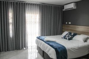 a bedroom with a bed and a large window at The Rainbowtree B&B in Gaborone