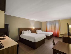 サバンナにあるMainStay Suites Savannah Midtownのベッド2台とデスクが備わるホテルルームです。
