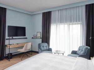 um quarto de hotel com uma cama e duas cadeiras e uma televisão em Radisson Hotel Budapest BudaPart em Budapeste