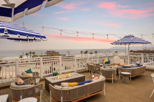 uma varanda com cadeiras e mesas e vista para o mar em Inn at the Pier Pismo Beach, Curio Collection by Hilton em Pismo Beach