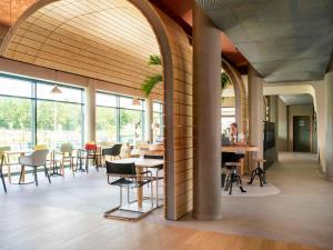 duży pokój ze stołami, krzesłami i oknami w obiekcie greet hotel Cernay Mulhouse w mieście Cernay