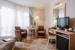 a hotel room with a desk with a television and a bedroom at Kyivska Russ Resort Medical&Spa in Skhidnitsa