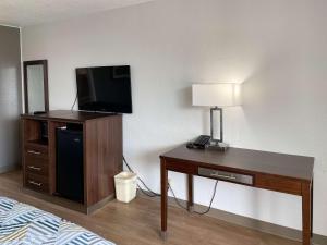 a room with a bed and a desk with a television at Motel 6 Opelika AL in Opelika