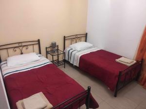 two beds in a small room with red sheets at SANTA MAURA in Lefkada Town