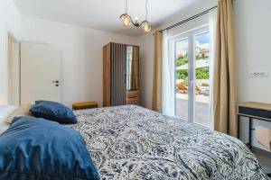 a bedroom with a bed with blue pillows and a window at Villa Janie - Modern Pool Apartments Splitska in Splitska +55 photos