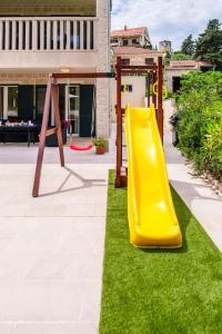 a playground with a yellow slide on the grass at Villa Janie - Modern Pool Apartments Splitska in Splitska