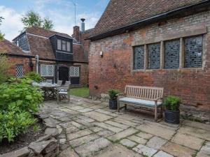 a patio with a bench and a table in front of a brick building at Townhouse with cathedral views in Kent