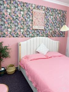 Dormitorio rosa con cama y pared de flores en FlowerGod Apartments - BlackPink HomeStay, en Hanói