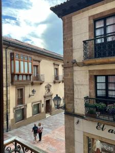 two people walking down a street between two buildings at La mejor ubicación en Oviedo. Casco histórico. in Oviedo