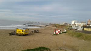 a beach with a yellow shack and the ocean at Bahía Estrada MDP in Mar del Plata
