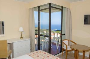 a bedroom with a bed and a table and a balcony at Dorisol Mimosa Studio Hotel in Funchal