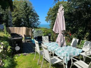 une table et des chaises avec un parasol et un grill dans l'établissement Spacieux appartement jardin, BBQ, vue sur mer, Trouville, à Trouville-sur-Mer