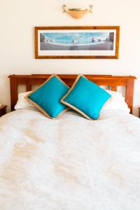 a bed with two blue pillows on it at Anglesea Rivergums in Anglesea