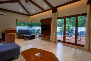Tropical villa by Happyinch في Saligao: غرفة معيشة مع أريكة وطاولة