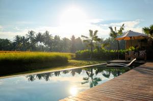 een zwembad met een tafel en een parasol naast een resort bij The Samara Villas & Restaurant in Ubud