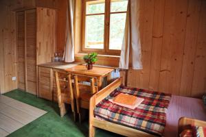 a bedroom with a bed and a desk and a window at Folwark Toporzysko in Jordanów