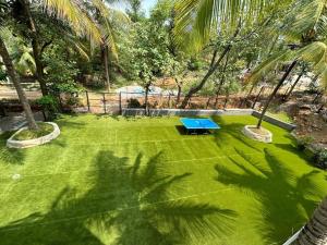 un patio verde con una mesa azul en Soul Nest-Pyramid Valley International Bengaluru en Bangalore
