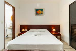 um quarto com uma grande cama branca e duas mesas em Pousada Casa Amarela em Ilhabela