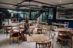 una mujer sentada en una mesa en un restaurante en Natee The Riverfront Hotel Kanchanaburi en Kanchanaburi