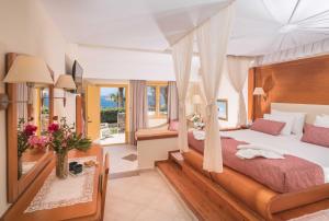 een slaapkamer met een groot bed met een baldakijn bij Kalypso Cretan Village Resort & Spa in Plakias