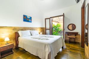 a bedroom with a bed and a table and a window at Pousada Casa Amarela in Ilhabela
