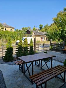 a picnic table and two benches in front of a fence at Kvartura z dvorukom in Kamianets-Podilskyi