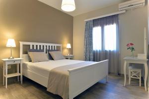 a bedroom with a white bed with two tables and a window at Villa Gaia in Dassia
