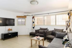Una sala de estar con un sofá y un televisor. en Netanyas One Bedroom Beachside Escape, en Netanya