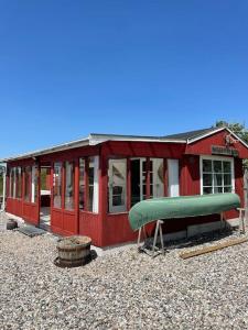 a red house with a green infront of it at Fjordhytten. Rebuild train wagon from 1937. in Odense