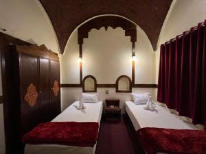 two beds in a room with red curtains at Elphardous Oasis Hotel in Luxor