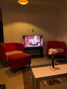 a living room with two red chairs and a television at דירת גג ים עכו חיפה נוף מרהיב in Acre