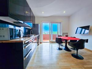 cocina con mesa roja y sillas negras en Terraced Park View Penthouse, en Roma