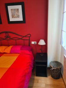 a red bedroom with a bed with a colorful blanket at Acogedor apartamento Estacion de esqui San Isidro in San Isidro