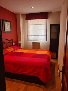 1 dormitorio con 1 cama con manta roja y amarilla en Acogedor apartamento Estacion de esqui San Isidro en San Isidro