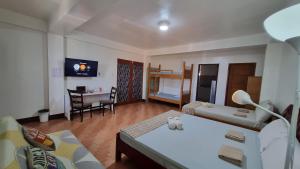 Habitación con 2 camas y sala de estar con mesa. en PARB Tuguegarao en Tuguegarao