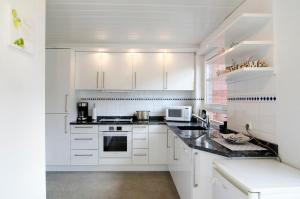 a white kitchen with white cabinets and appliances at Fewo am Deich in Wilhelmshaven