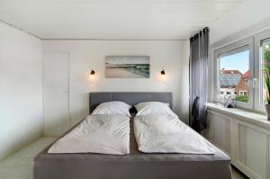 ein Schlafzimmer mit einem Bett mit zwei Kissen und einem Fenster in der Unterkunft Fewo am Deich in Wilhelmshaven