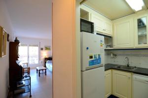 cocina con armarios blancos y nevera blanca en Apartamento Grecia 2 D, en L'Estartit