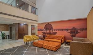 a lobby with a couch and chairs and a painting at Treebo Tryst Baramasi By Jai Club Prime in Jaipur