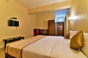 a bedroom with a large bed with a tv on the wall at Baga Fantacia Beach Inn in Calangute